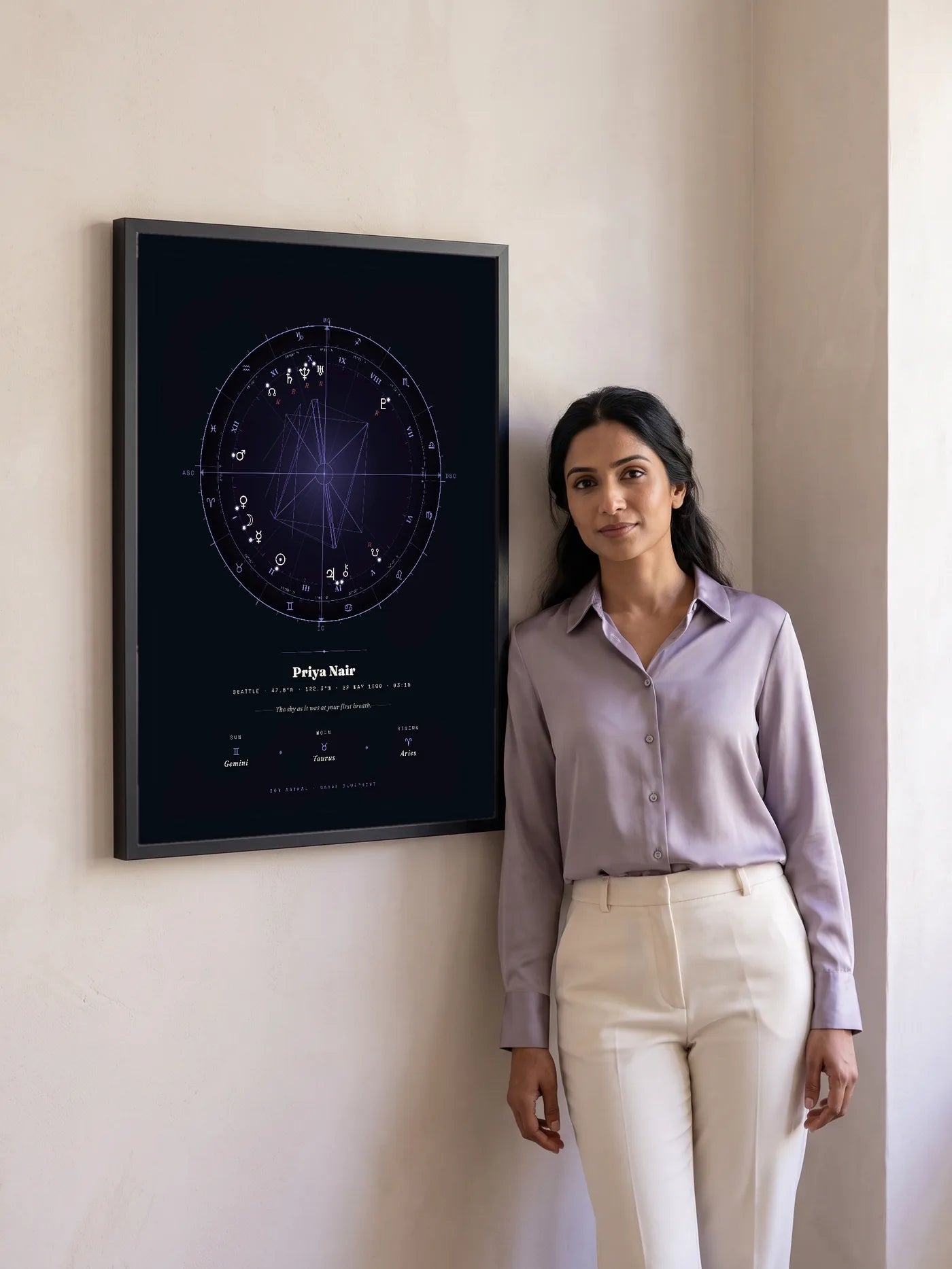 A woman in a lilac shirt stands beside a large black-framed Natal Blueprint in the violet Nocturne style.